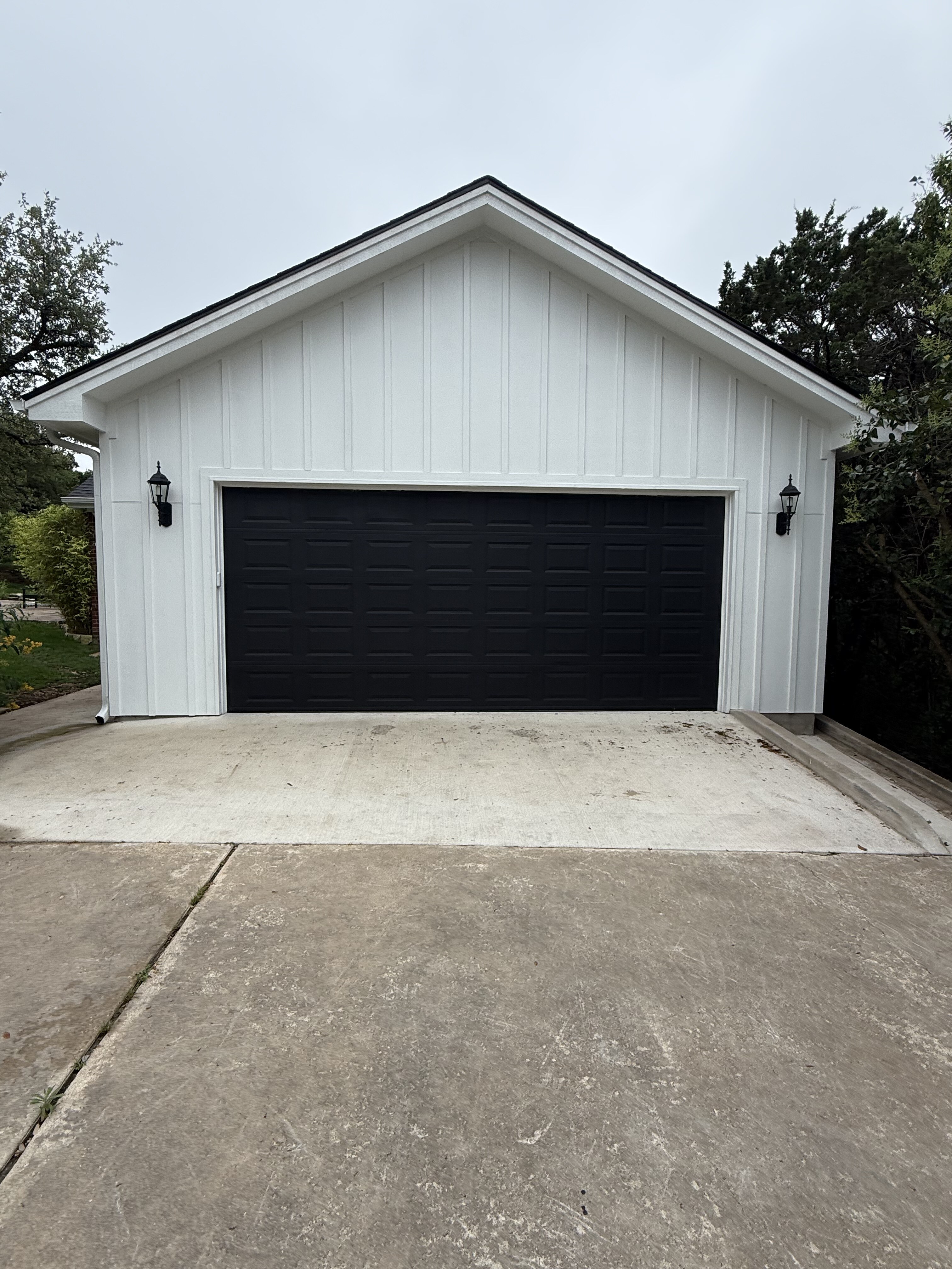 Custom detached garage with wood doors, stucco finish and decorative exterior lighting