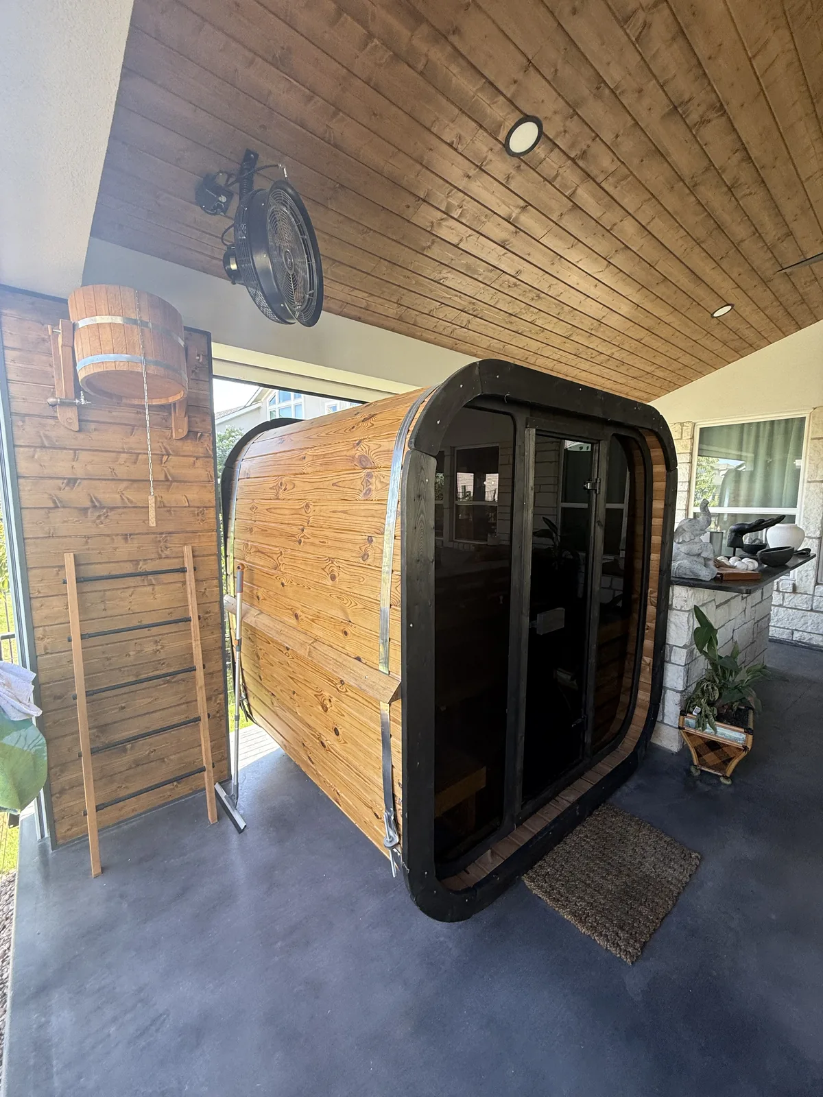 Barrel sauna installed beside the covered outdoor living space at the Rough Hollow project