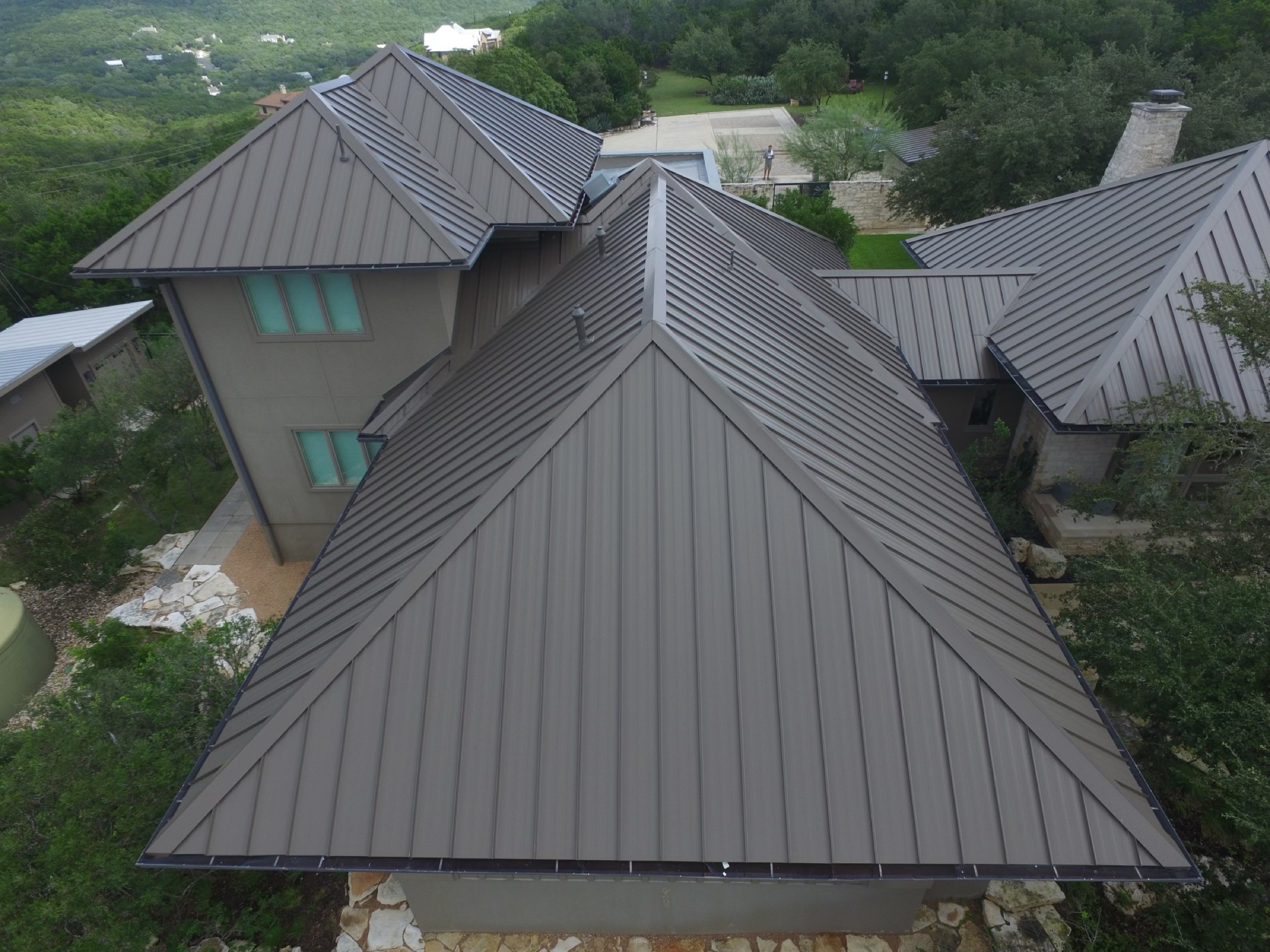 Close aerial view of standing-seam metal roof hips and intersecting roof planes