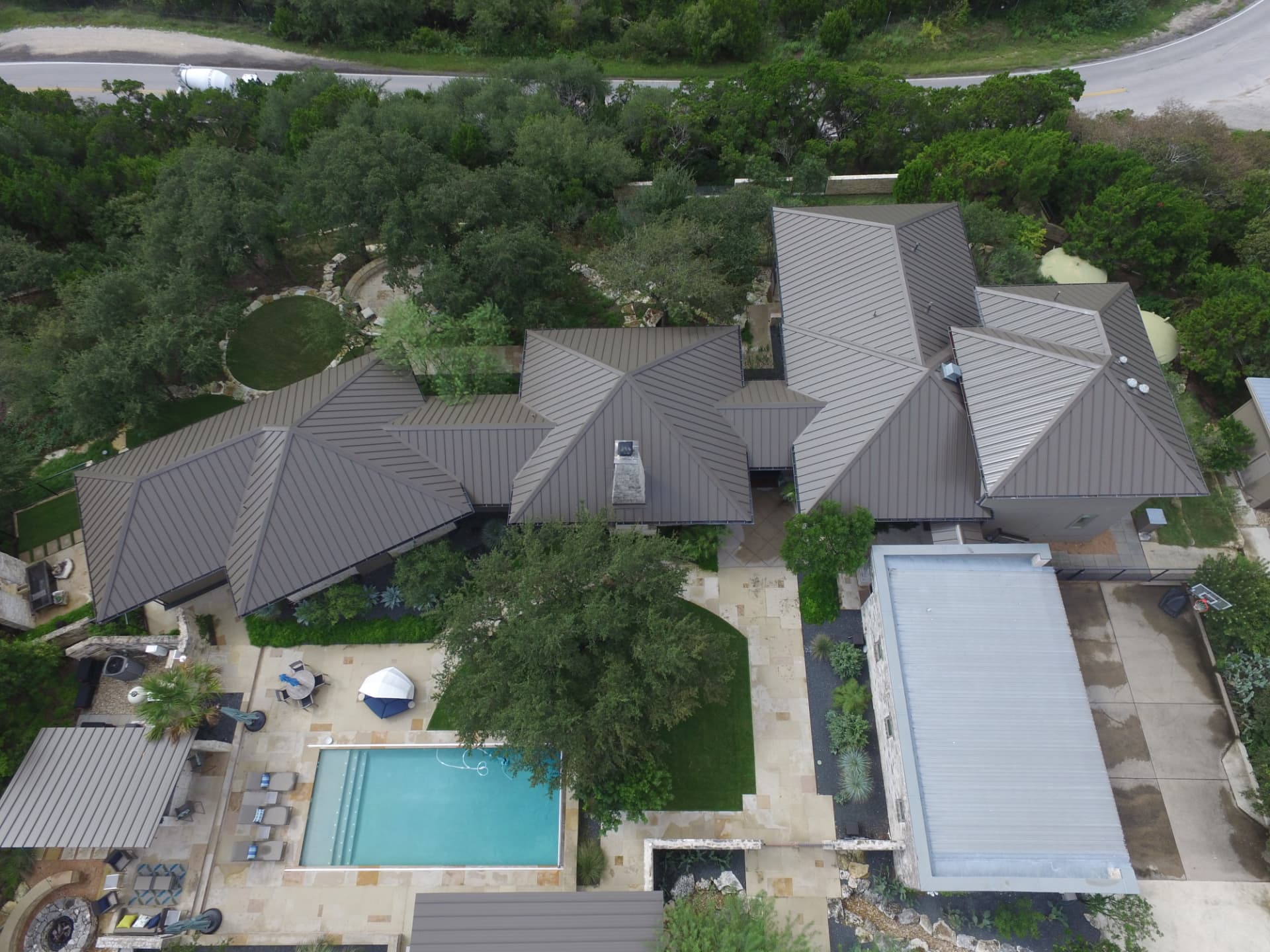 Aerial view of a home with a standing-seam metal roof, pool courtyard and outdoor living space