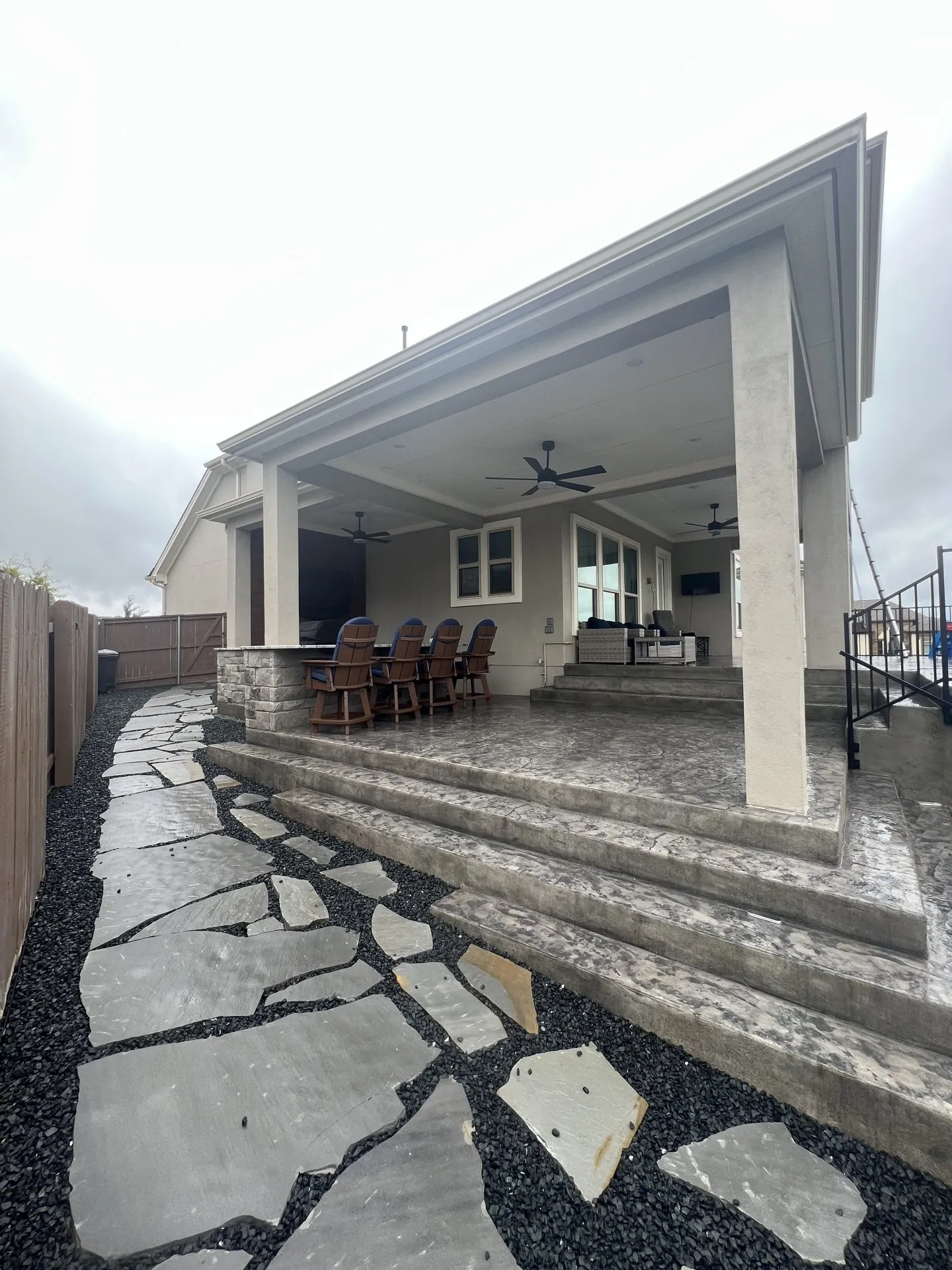 Gray attached patio cover connected to the home above a furnished outdoor terrace