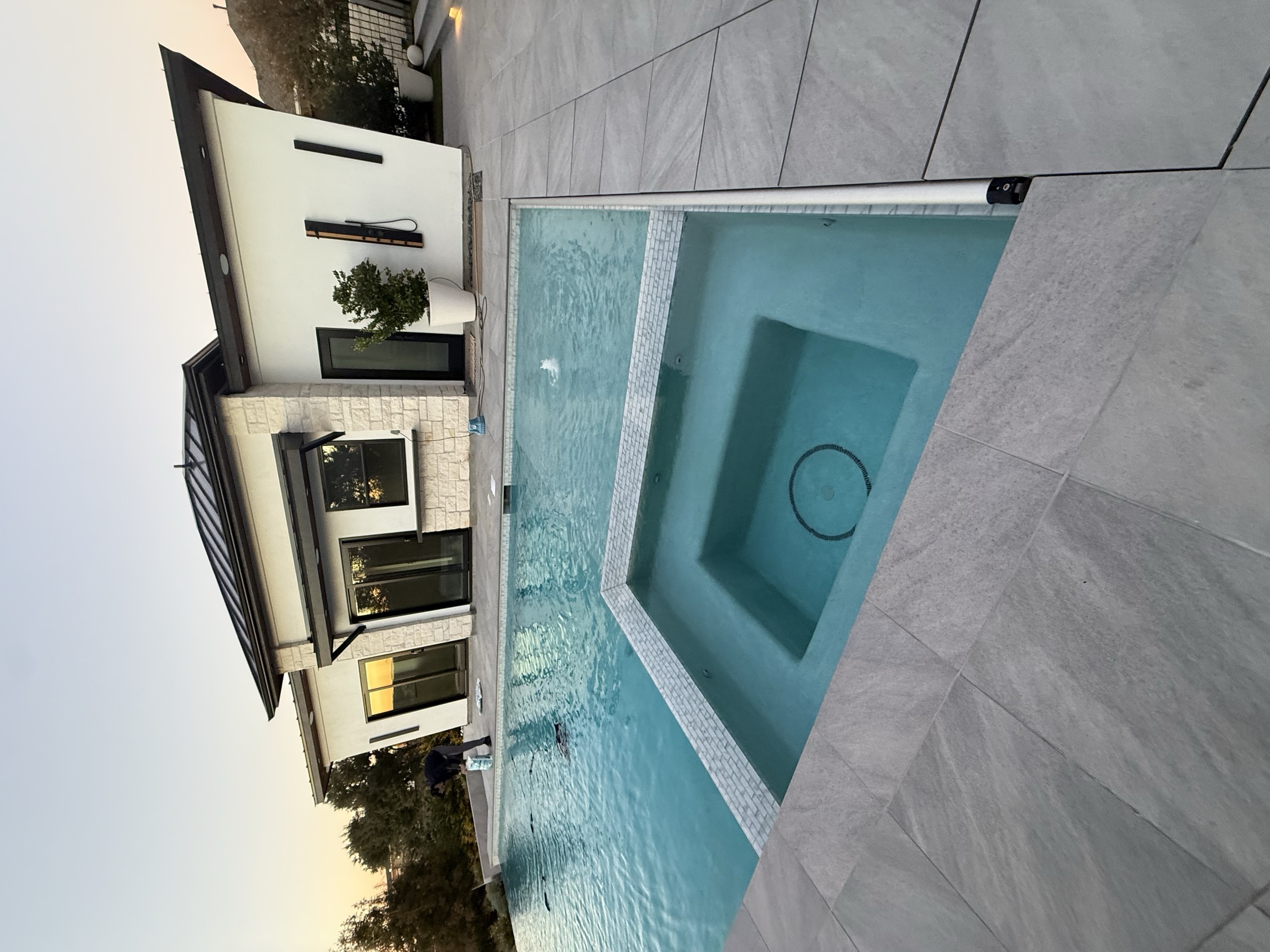 Modern white casita with dark metal roof beside a swimming pool and spa