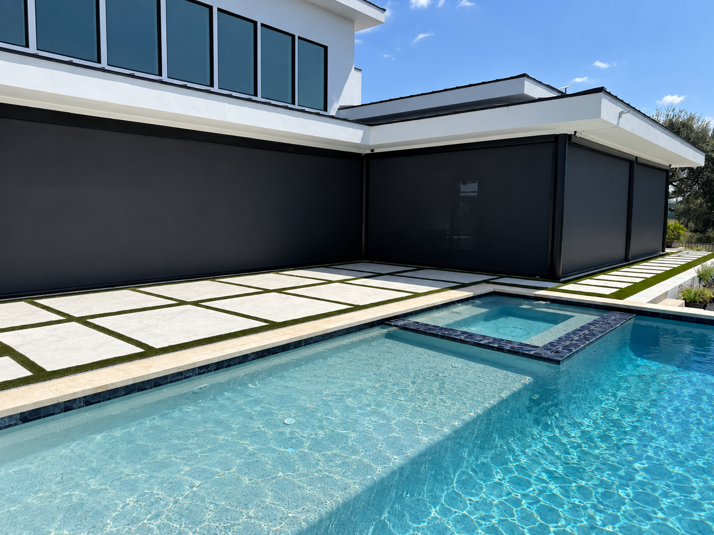 Modern poolside structure with retractable MagnaTrack screens, clean white trim, and a turquoise pool with geometric concrete decking
