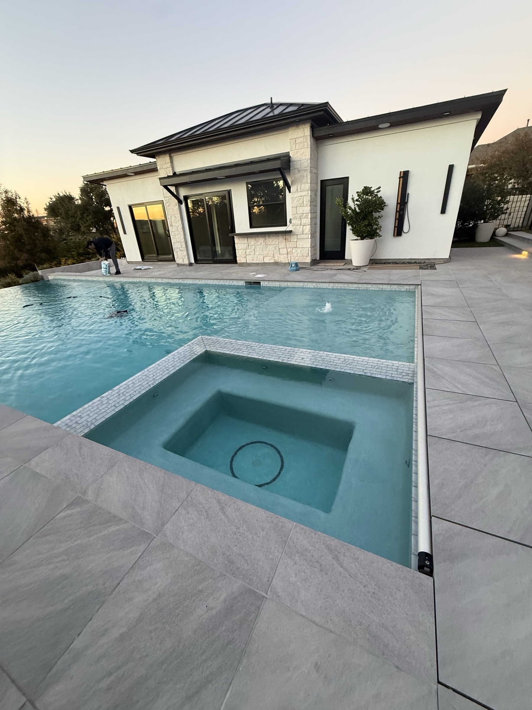 Modern white casita with dark metal roof beside a swimming pool and spa