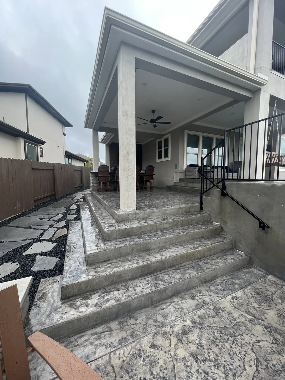 Attached gray patio cover with a roofline integrated into the existing two-story home