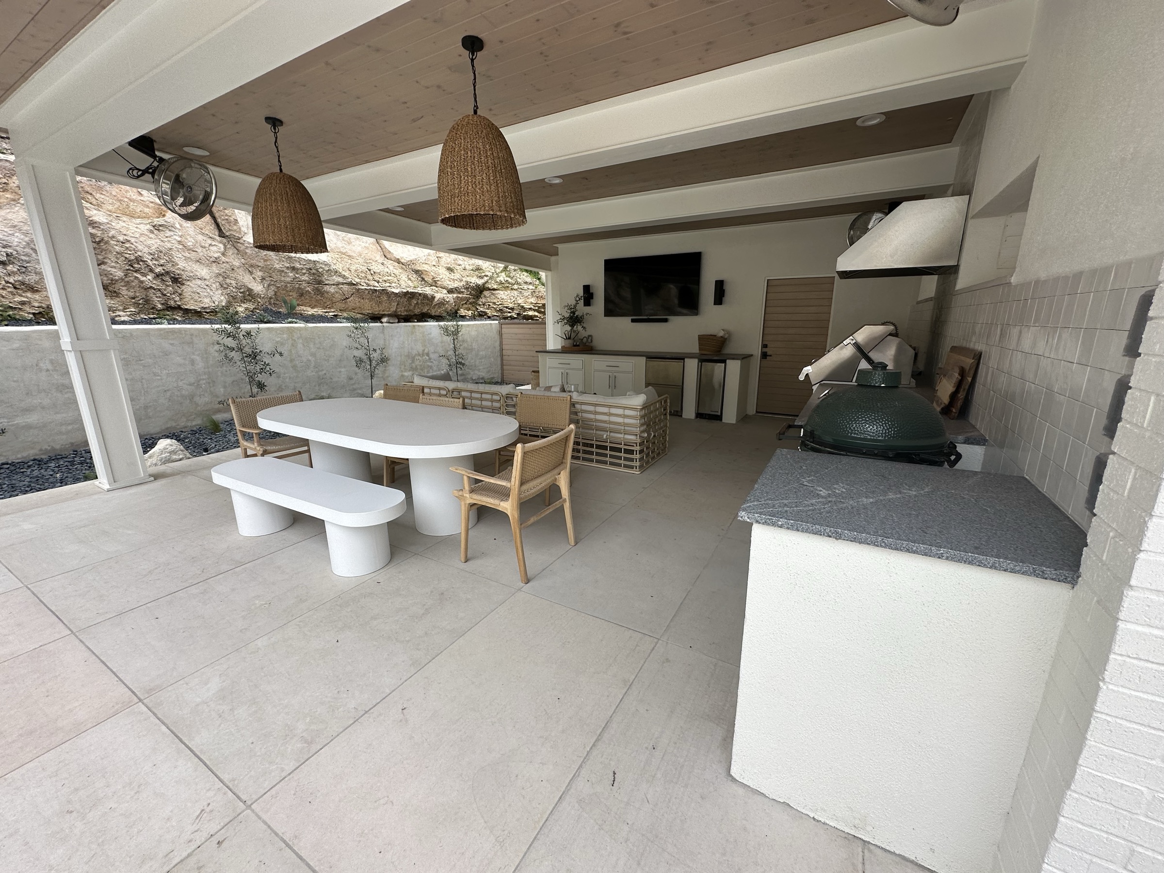 Pool house outdoor kitchen with a white dining table and built-in Big Green Egg