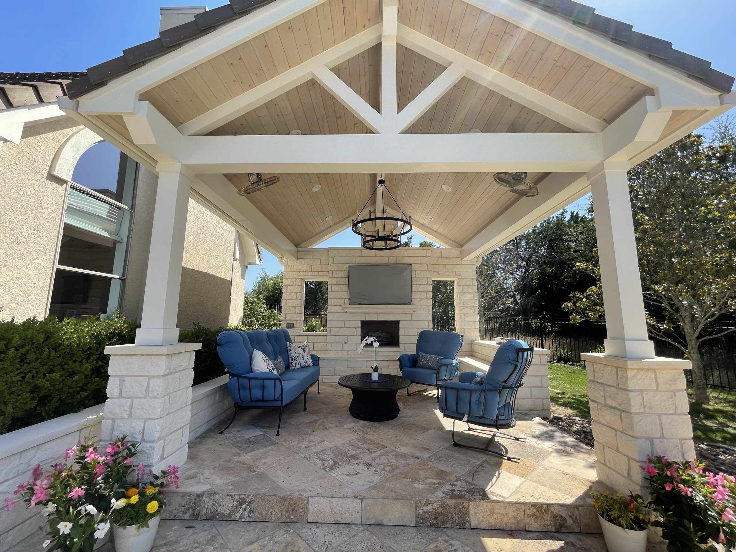 Gabled stone pool pavilion with blue seating and a fireplace