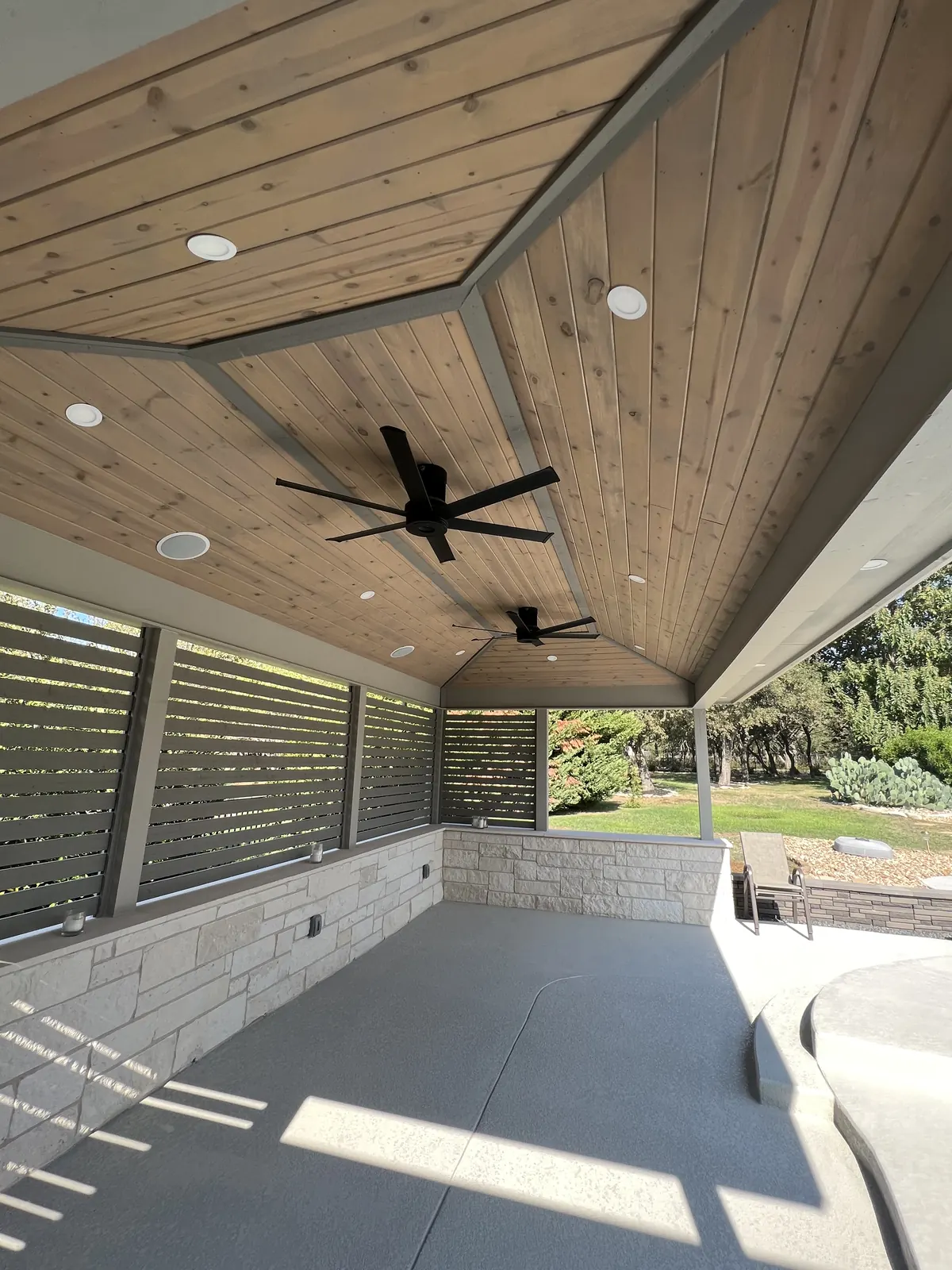 Vaulted patio cover with a louvered privacy wall and finished concrete floor