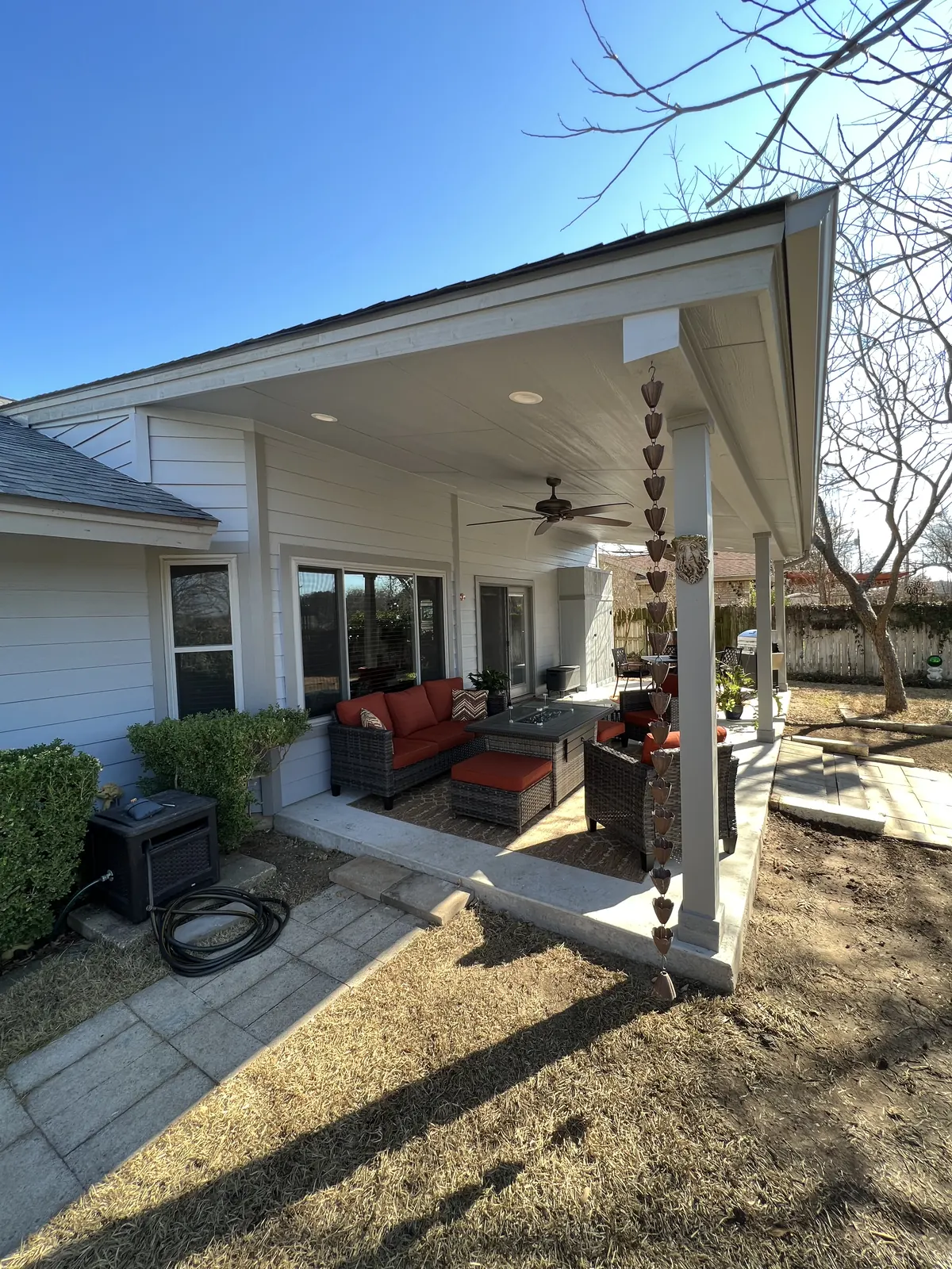 White painted patio cover with a ceiling fan over an outdoor lounge and dining set