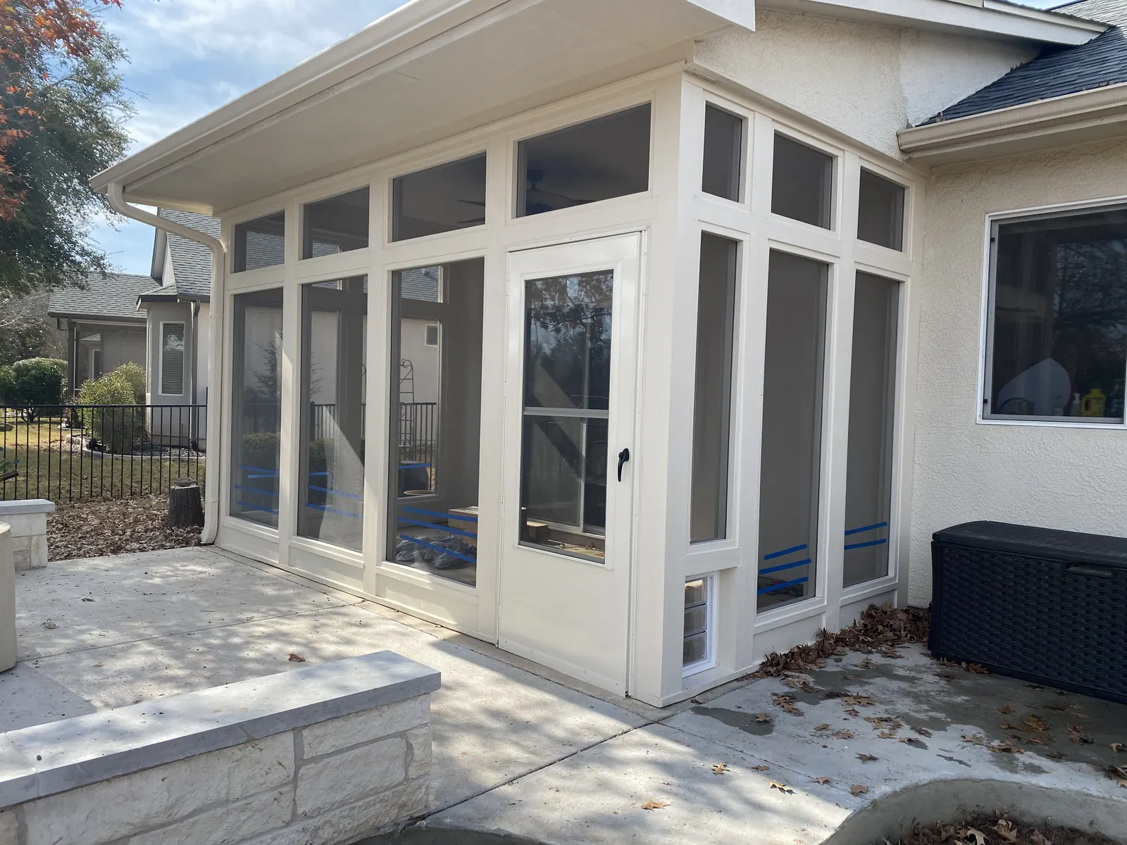 White framed fixed screen enclosure attached to a stucco home with landscaping
