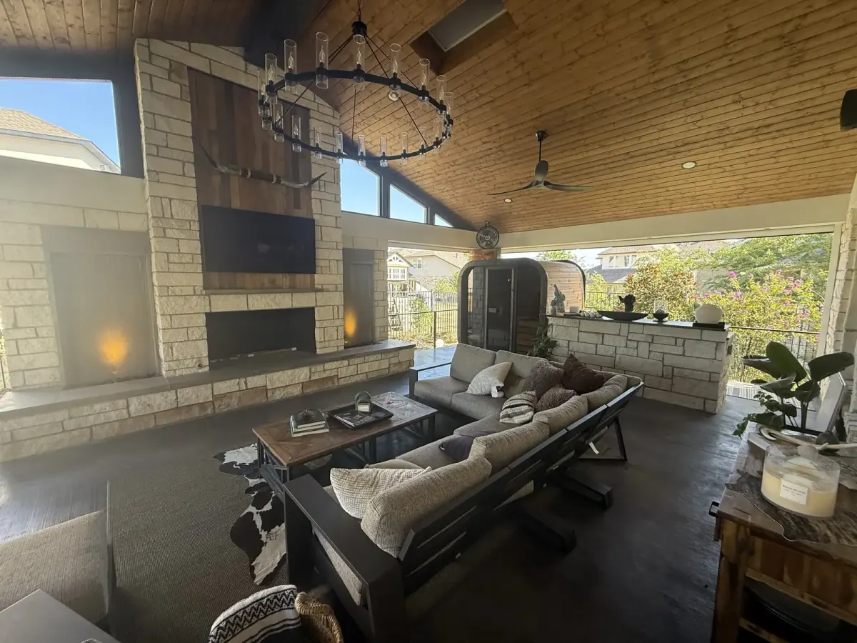 Finished vaulted Rough Hollow living room with a stone fireplace, chandelier and lounge seating