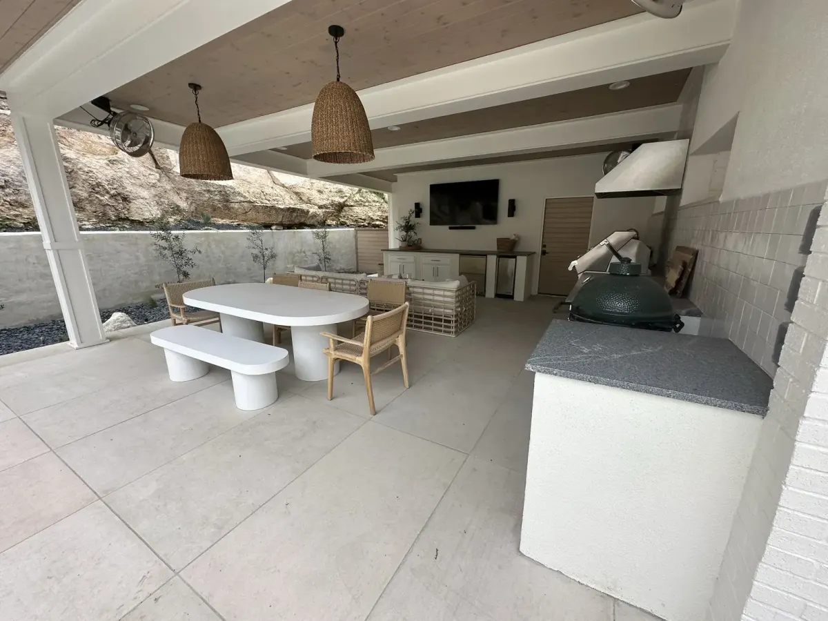 Pool house outdoor kitchen with a white dining table and built-in Big Green Egg