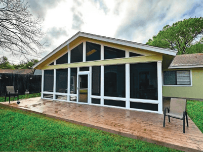 House with a large screened porch and a grassy yard with two chairs in Austin, TX