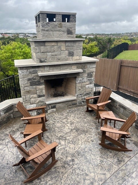 Outdoor stone fireplace patio with Adirondack chairs, showcasing exterior design in Austin, TX